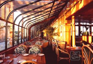 A restaurant with tables and chairs in the sun.