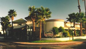 A building with palm trees on the corner of it.
